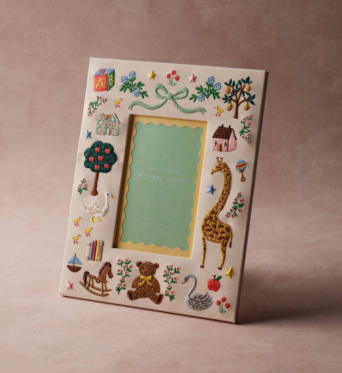 Rifle Paper Co. Storybook Embroidered Picture Frame featuring colorful nursery embroidery: blocks, houses, trees, animals, and toys.