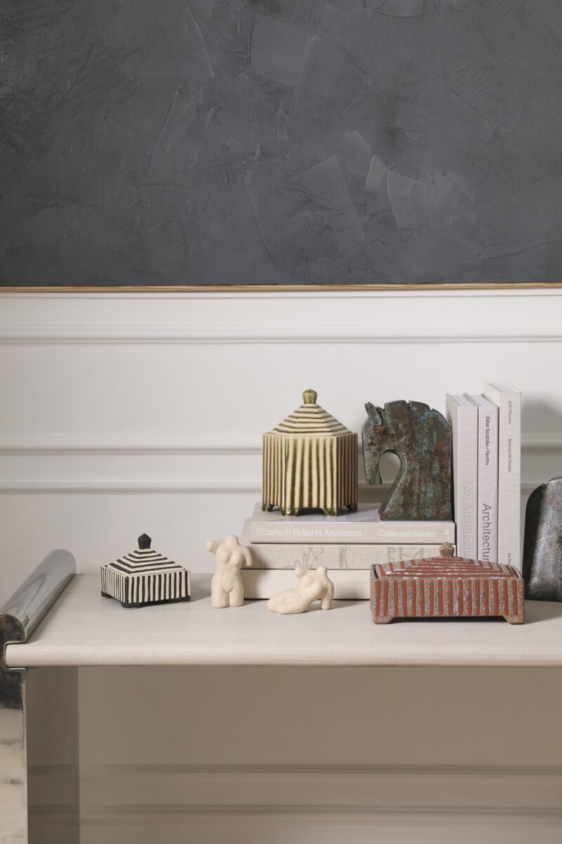 Banda Decorative Box, a striped accent decor piece, styled with other decorative boxes, sculptures, and books on a white table.